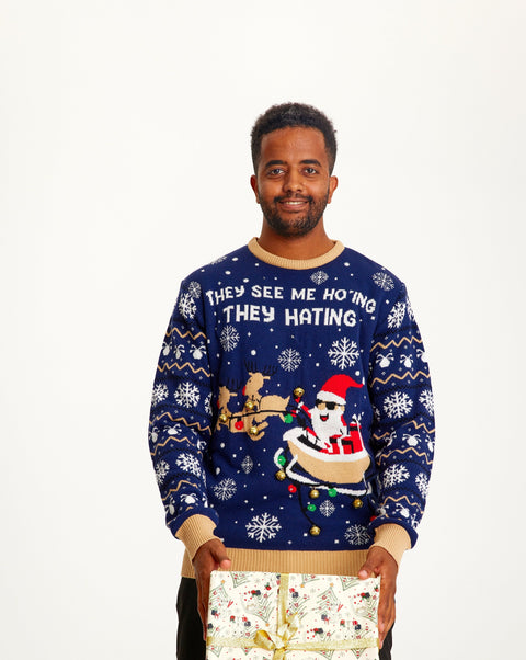 En smilende mand med en hvid julegave iført en blå julesweater.