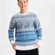 En smilende mand med hænderne i lommen iført en blå julesweater.